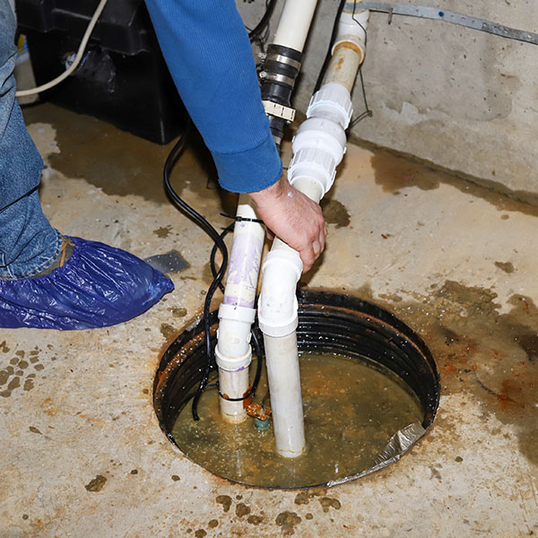 Plumber repairing a sump pump in a flooded basement