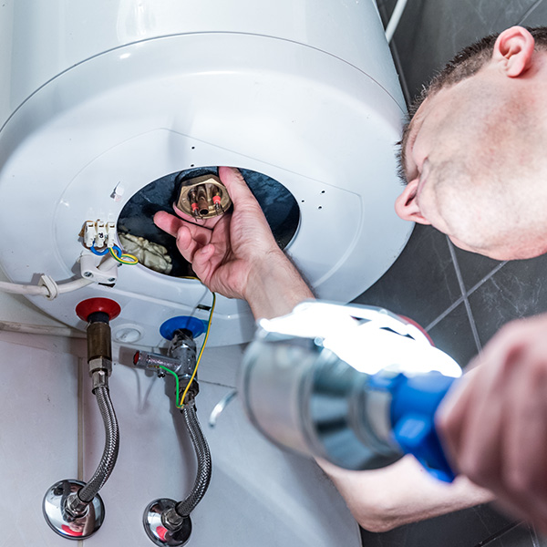 Man in bathroom repairing electric boiler