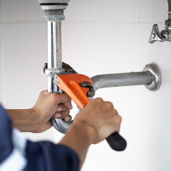 Plumber fixing bathroom pipes under the sink