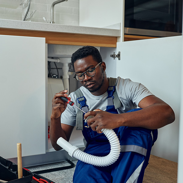 Plumber in uniform fixing kitchen sink