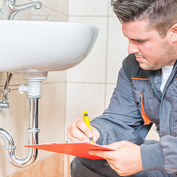 Plumber with clip board performing an inspection