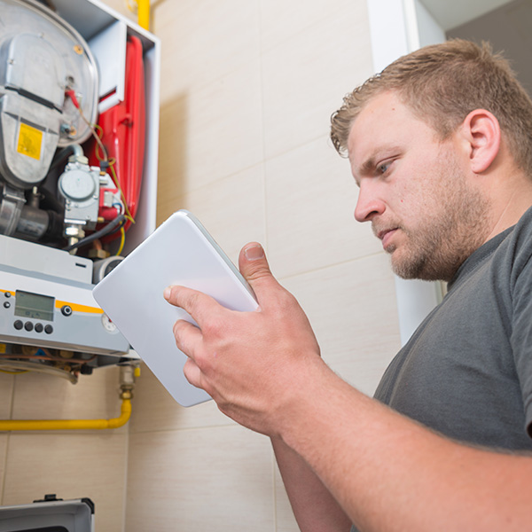 Technician repairing gas furnace using digital tablet