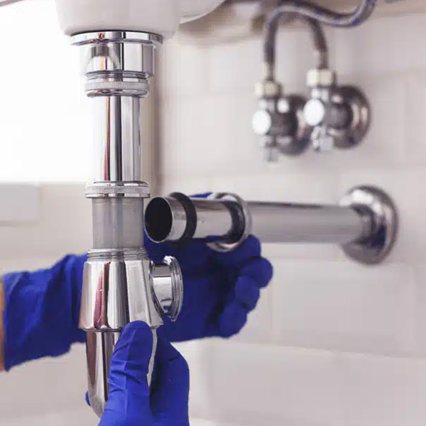 Plumber fixing pipes under sink