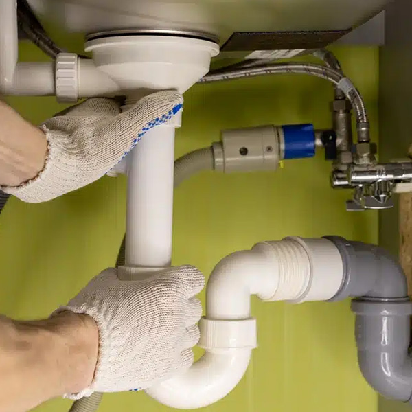 Plumber fixing bathroom pipes under the sink