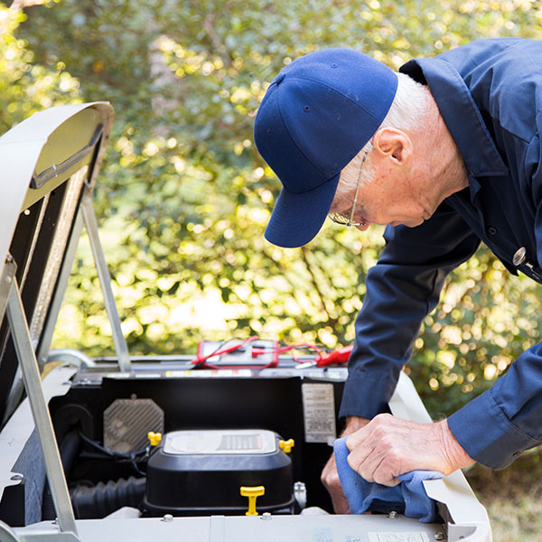 Senior air conditioner technician checking the oil in the generator