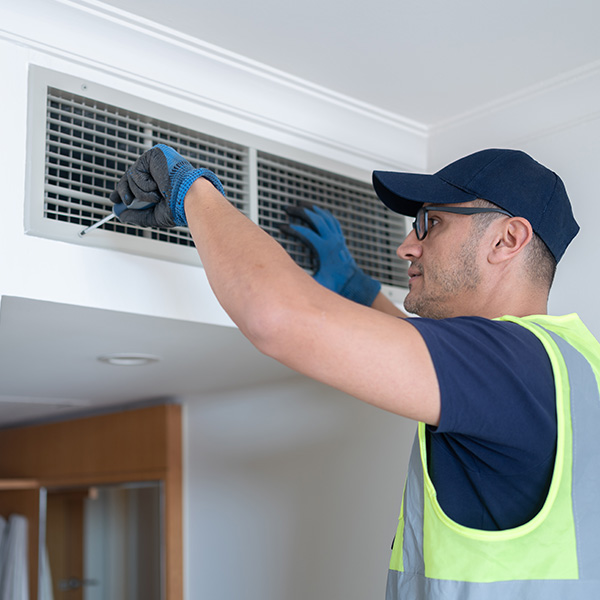 Repairman cleaning air conditioning wall mounted ventilation system on ceiling
